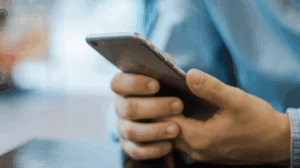Person in blue holding a smartphone with both hands.