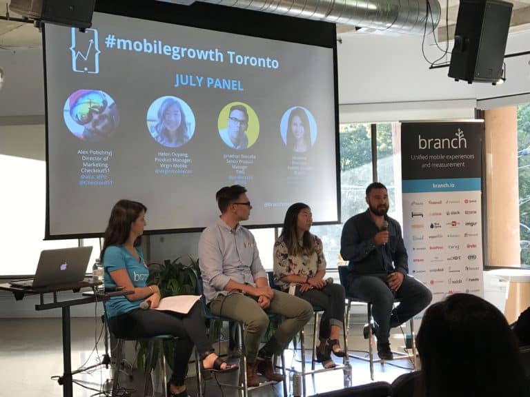 Four panelists sit in front of a screen displaying information at a MobileGrowth event.