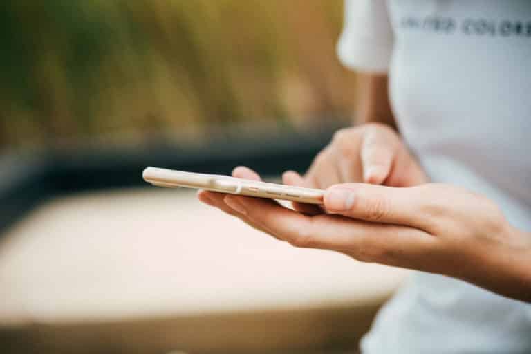 Close-up of hands typing on a smartphone.
