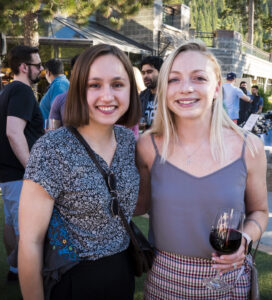 two ladies smiling at camera with wine 