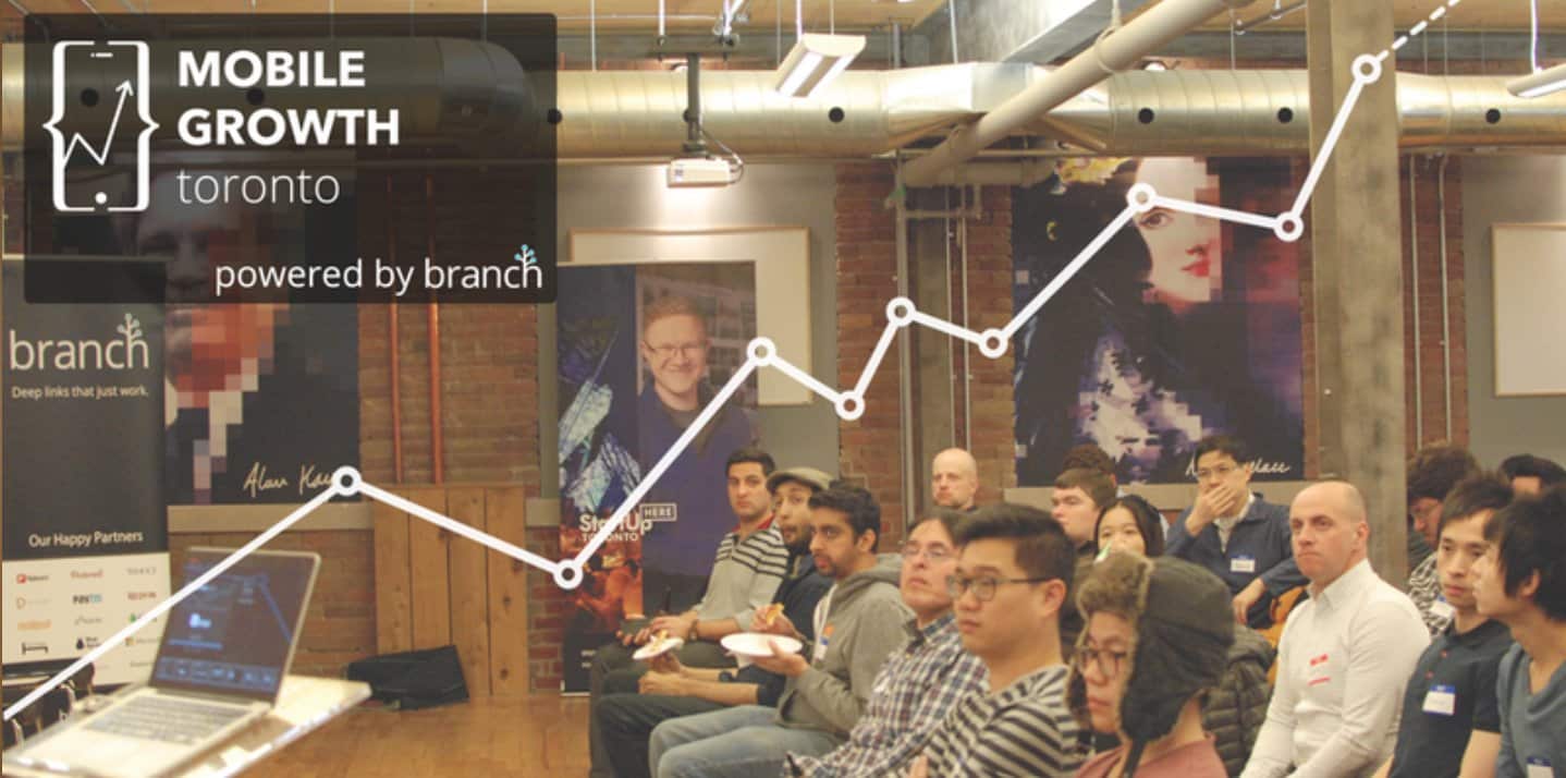 A presentation event in Toronto showcasing mobile growth strategies, featuring an audience engaged with visual data and branding displays.