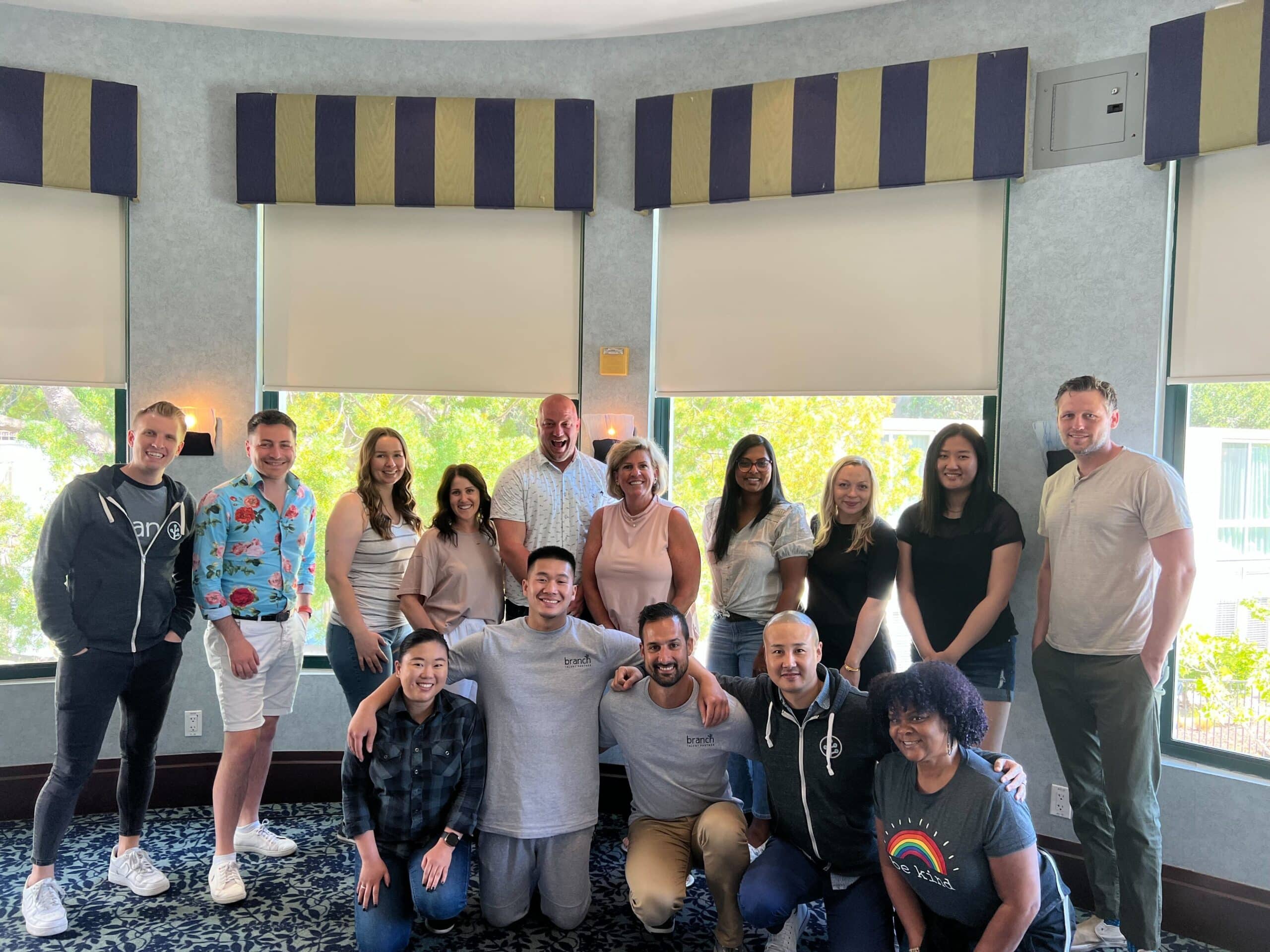 Photo of 15 Branch team members in front of a window.