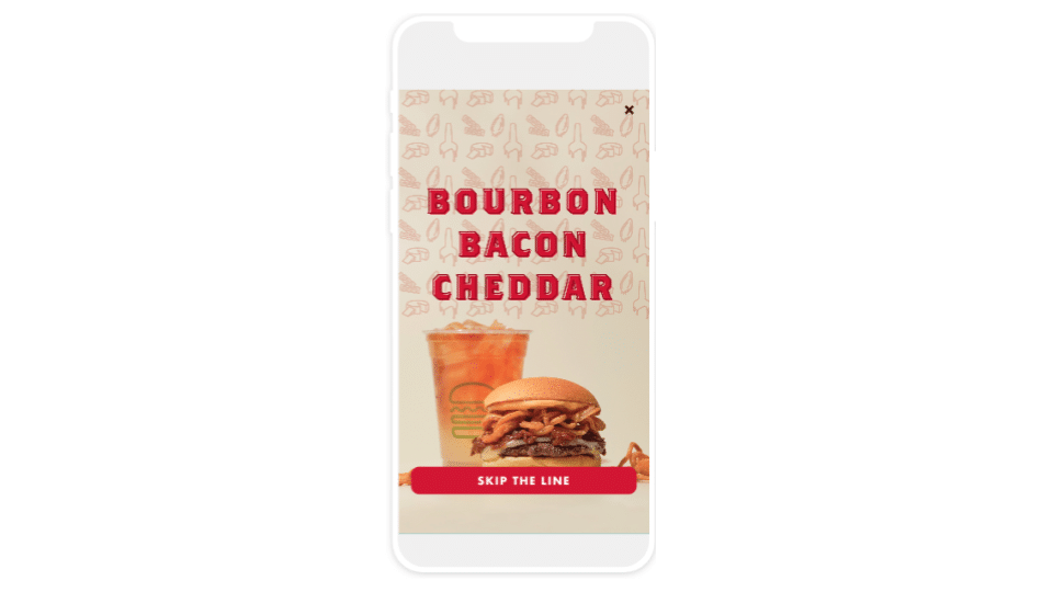 Bourbon Back Cheddar burger advertisement on a smartphone: An image of burger and drink, labeled "Bourbon Bacon Cheddar." A link at the bottom saying: "Skip the line" 